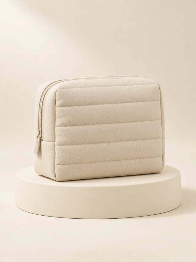 Channel Cosmetic Pouch in Oat, front view on a cream plinth