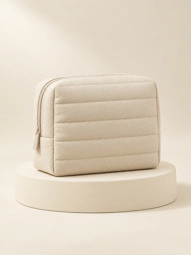 Channel Cosmetic Pouch in Oat, front view on a cream plinth
