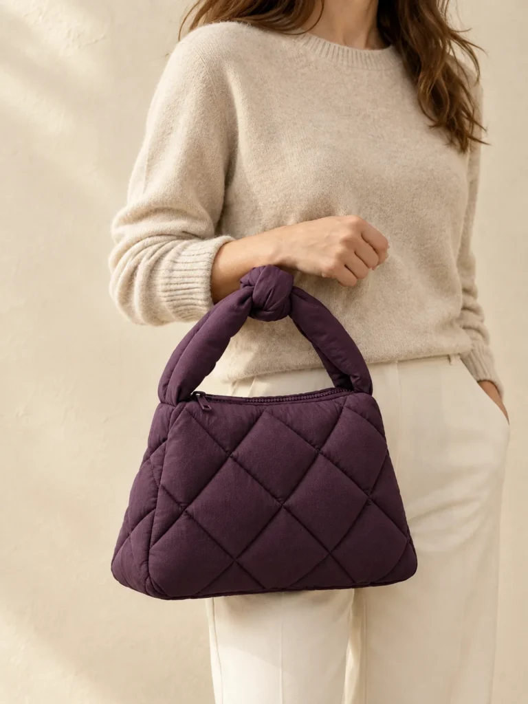 Knot Handle Puff in Plum, shown worn or carried to show its size