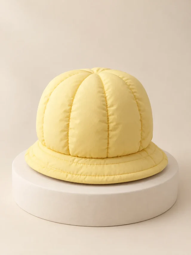 Puff Crown Hat in Butter, front view on a cream plinth