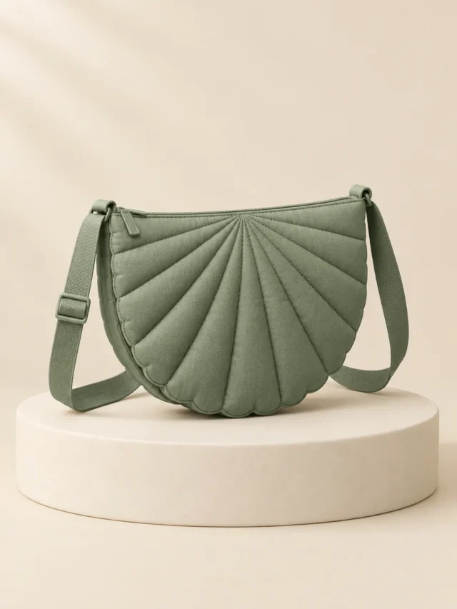 Scallop Moon Crossbody in Sage, front view on a cream plinth