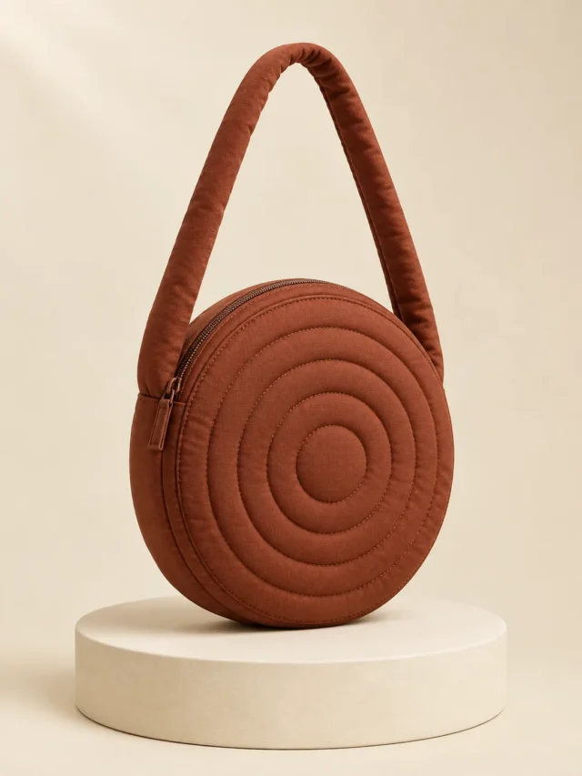 Stack Ring Disc in Chestnut, front view on a cream plinth