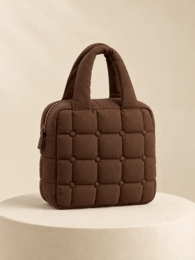 Tuft Button Mini in Cocoa, front view on a cream plinth