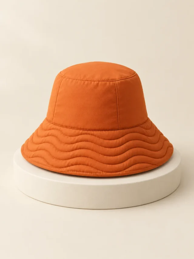 Wave Brim Bucket in Persimmon, front view on a cream plinth